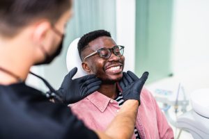 Man smiling during dental visit with dentist examining his teeth, showcasing positive dental care experience at Advanced Dentistry.