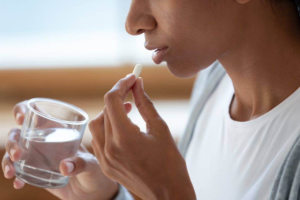 close up of a young woman taking a pill