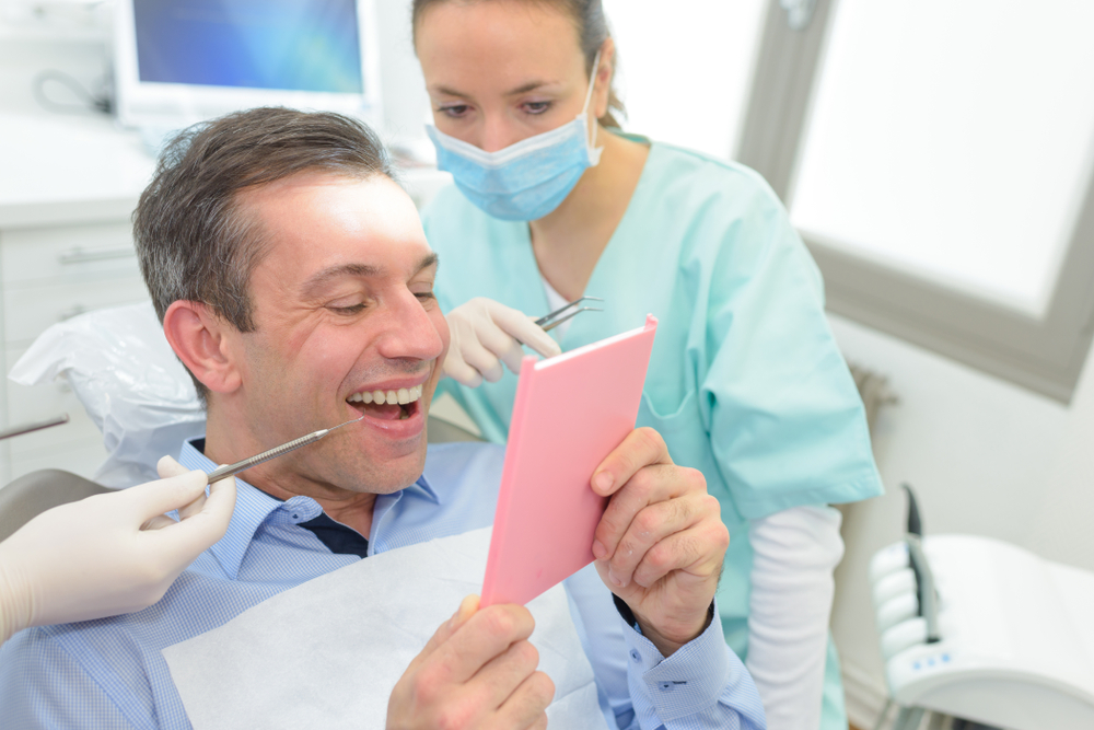 man sees smile in mirror at dental office