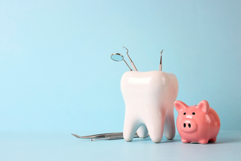 piggy bank next to model tooth filled with dental tools